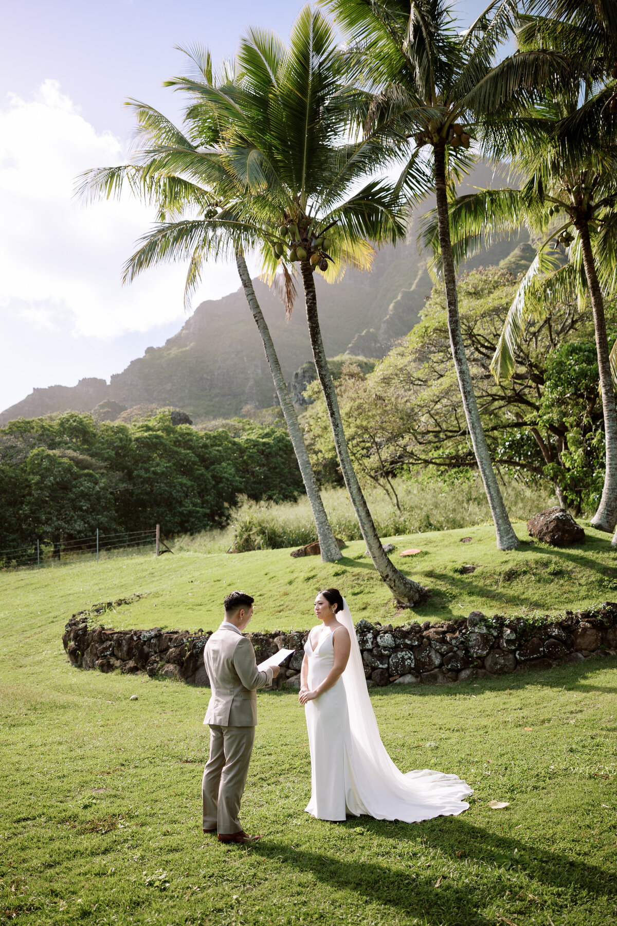 Bride and groom share their first look in Paliku Garden at Kualoa Ranch, framed by towering palm trees — by Kate Winters Photography.