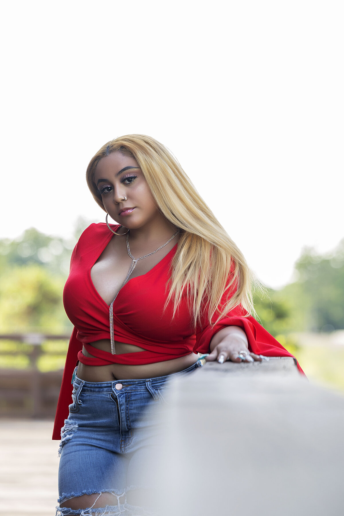 Senior girl with red shirt and blue jeans leaning on banister