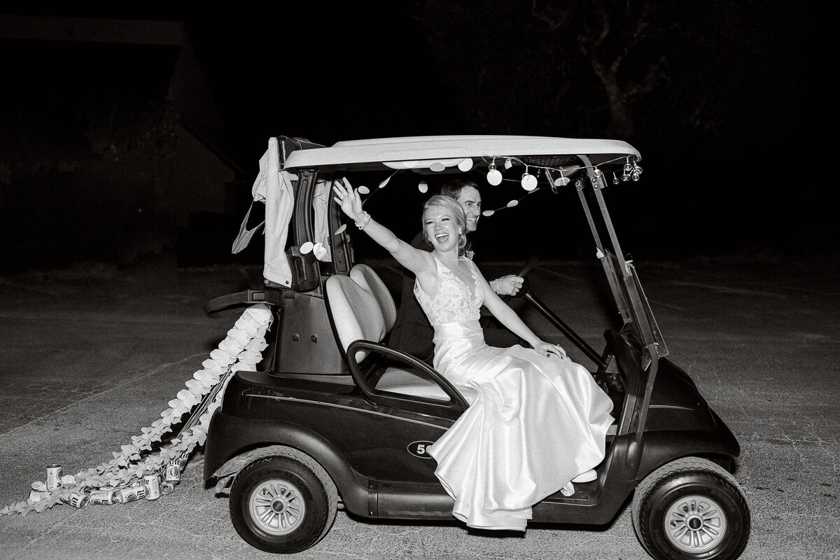Bride and groom wave while riding in golf cart at Tapatio Springs Hill Country Resort wedding