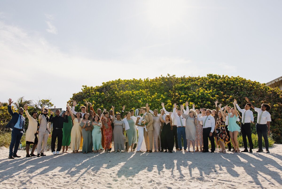 bride and groom and guests pose for portrait after wedding in south florida