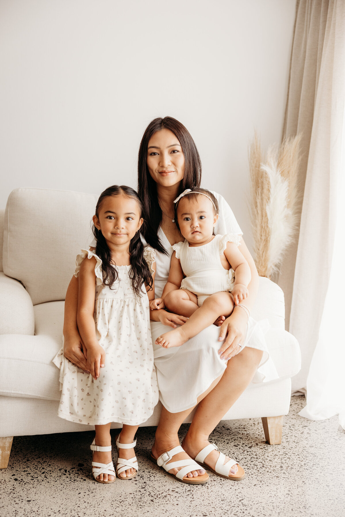 A mother and her two daughters posing for a family portrait in an auckland family photography studio