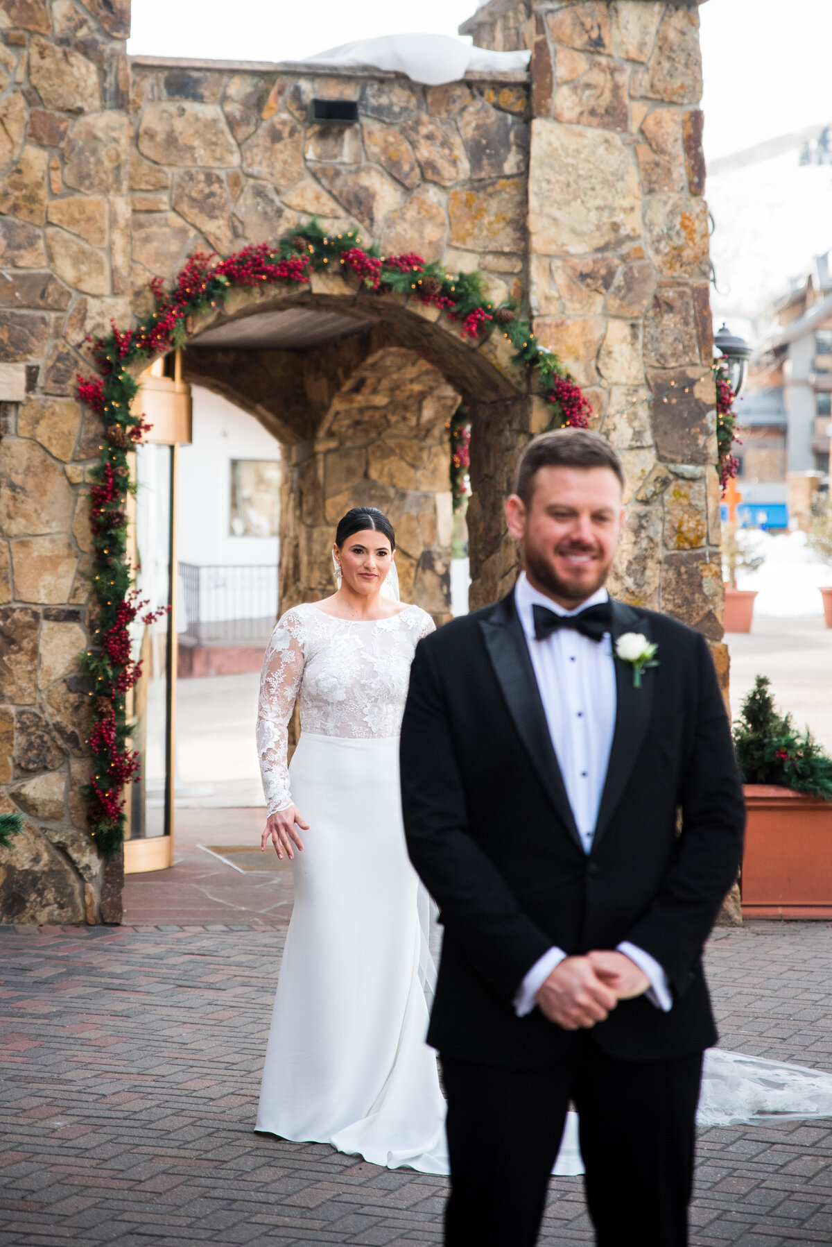 A groom waits in the foreground as his bride approaches for their first look in Vail, Colorado.