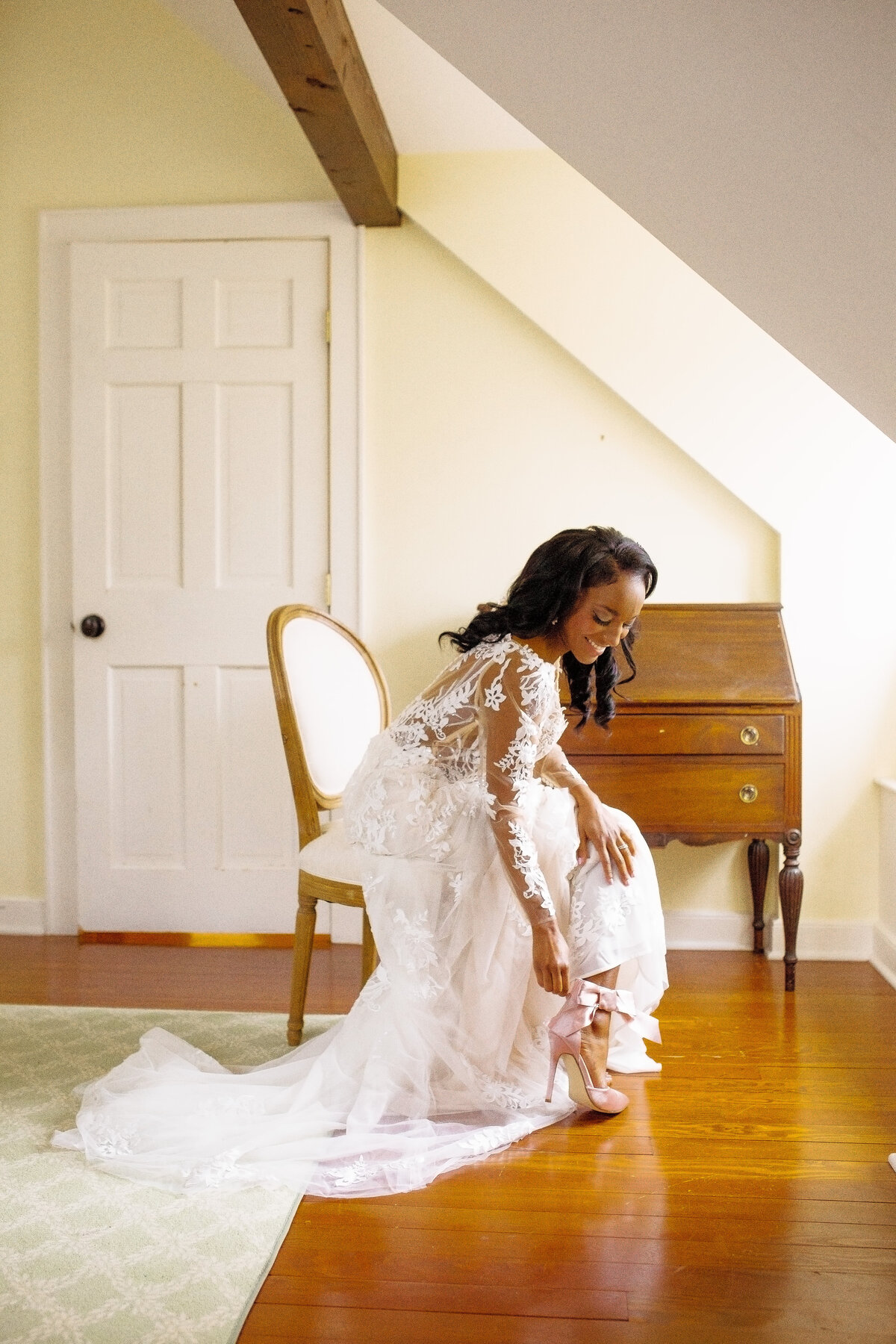 Black bride smiles as she puts her shoes on.