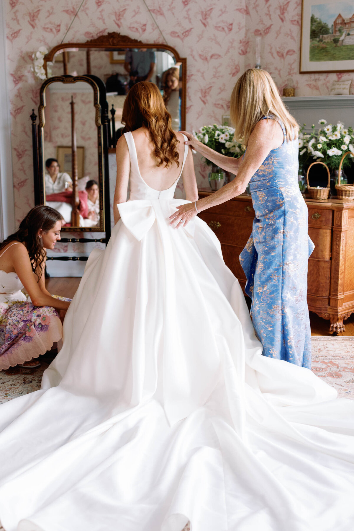 mother helps bride into sareh nouri gown with large bow