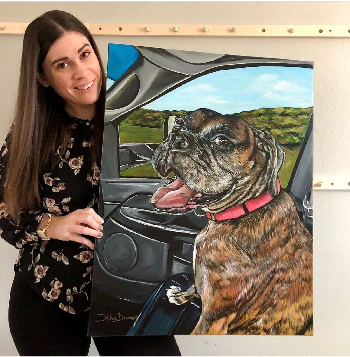 Debbie bowman next to a painting of a dog