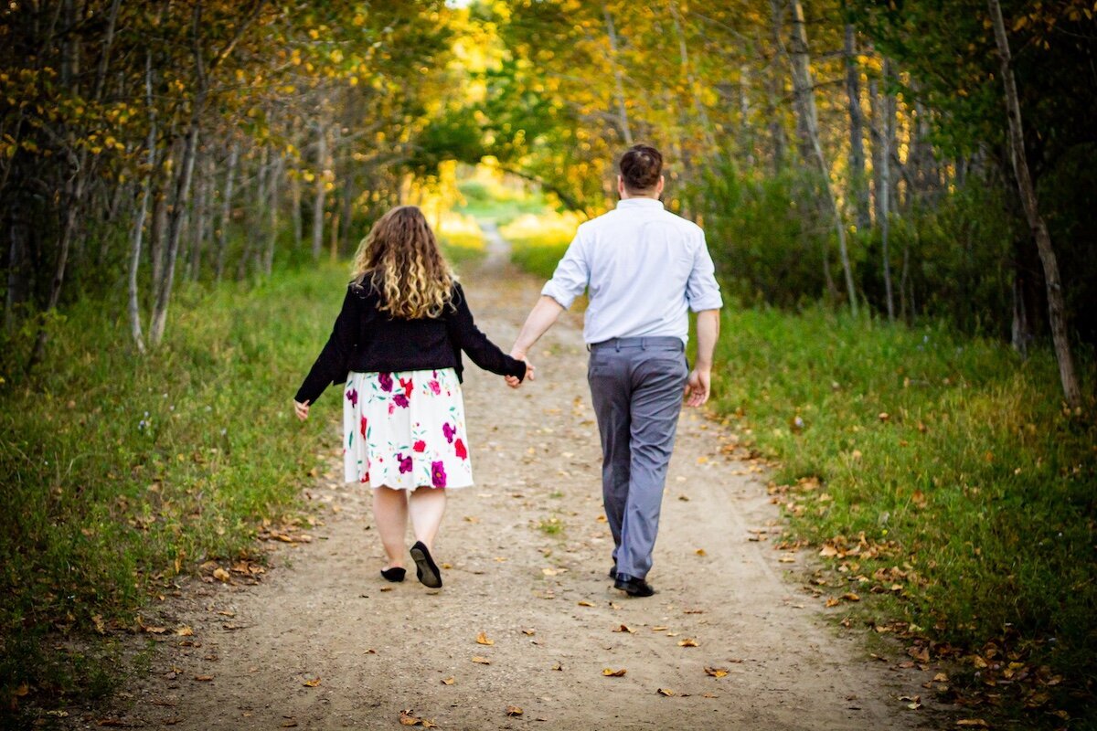 a couple walking away down a dirt road near Edmonton