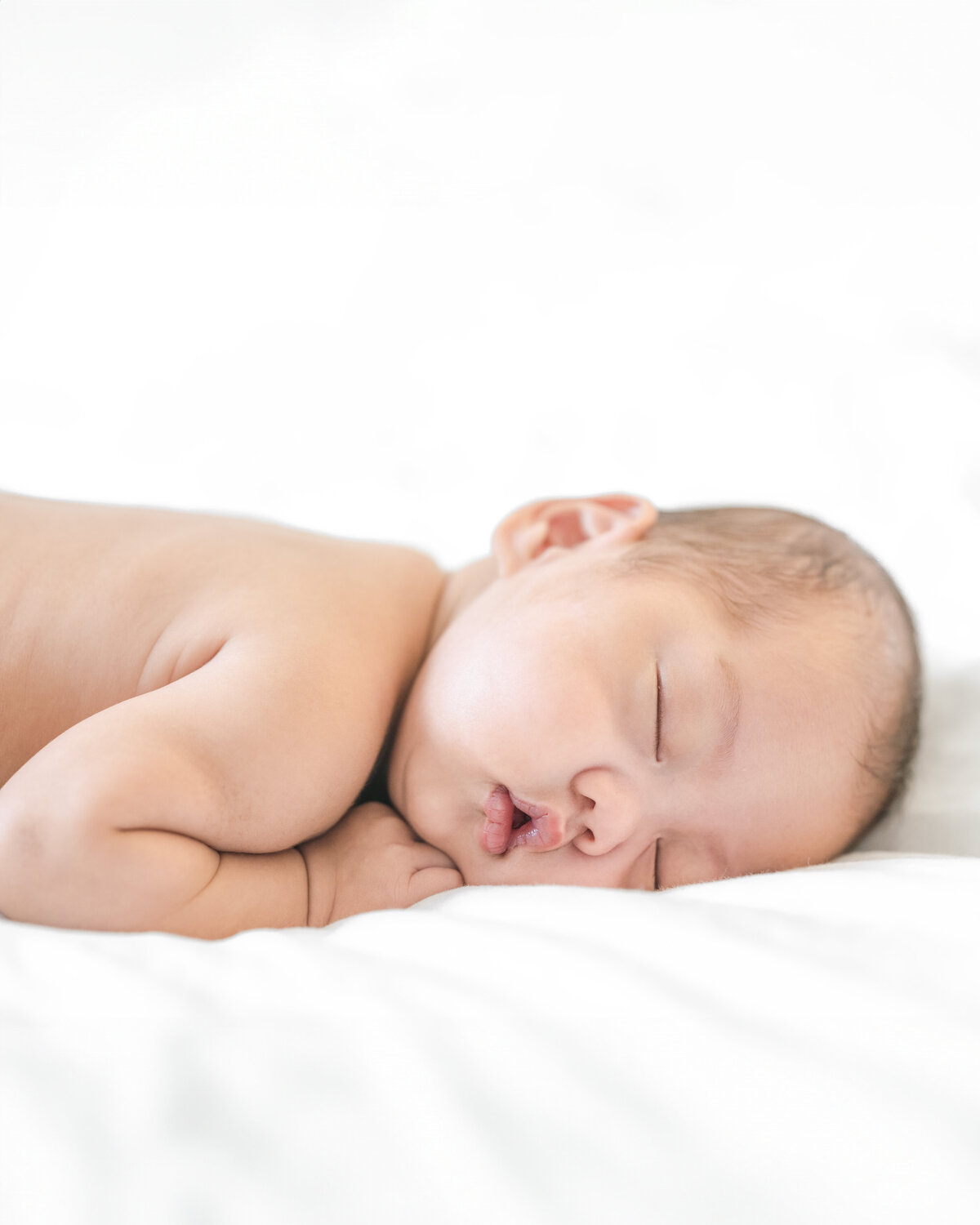 Adorable newborn baby sleeping peacefully on a white blanket, captured by a leading Los Altos newborn photographer 