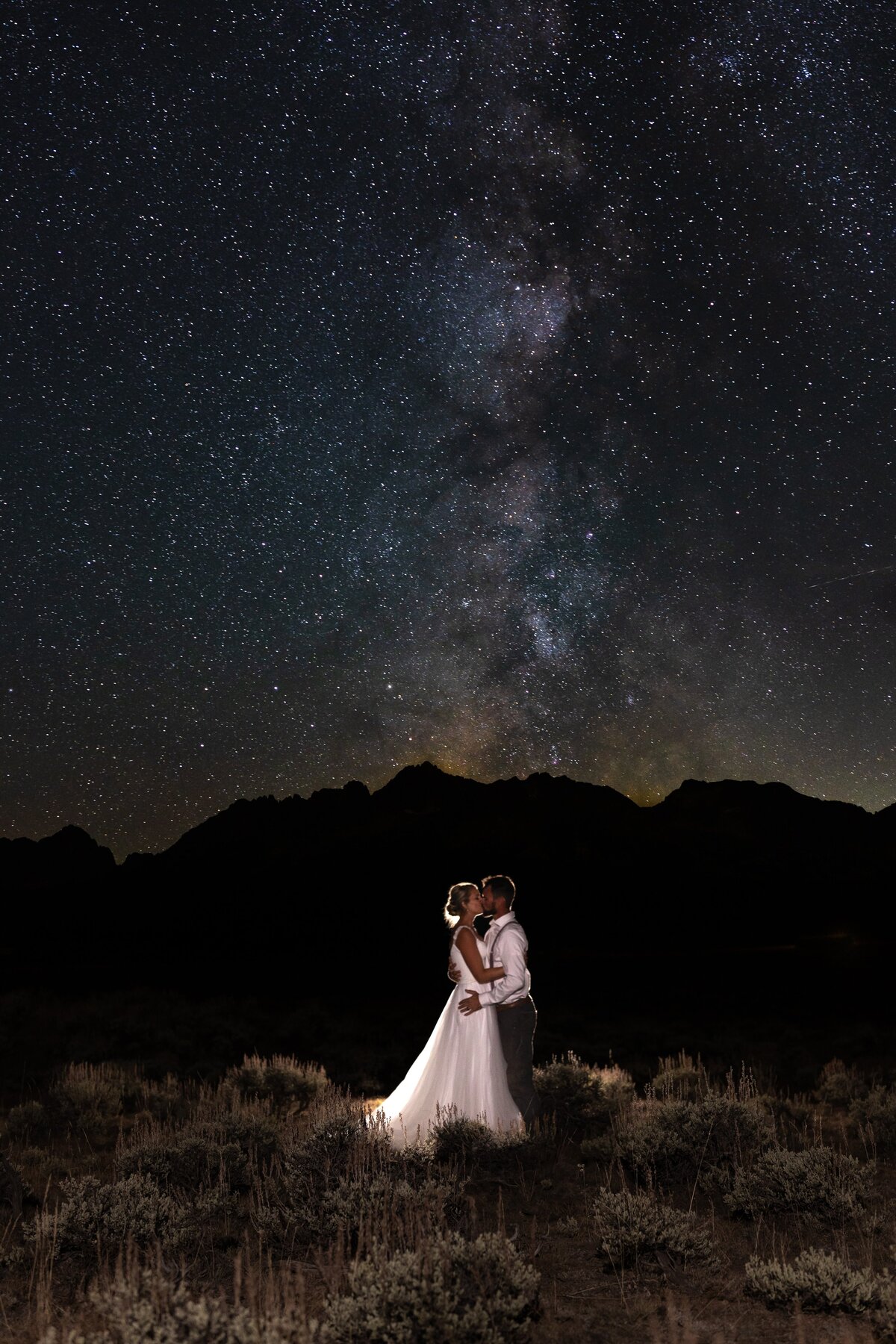 A couple kissing under the stars in front of the Sawtooth Mountains in Stanley, Idaho