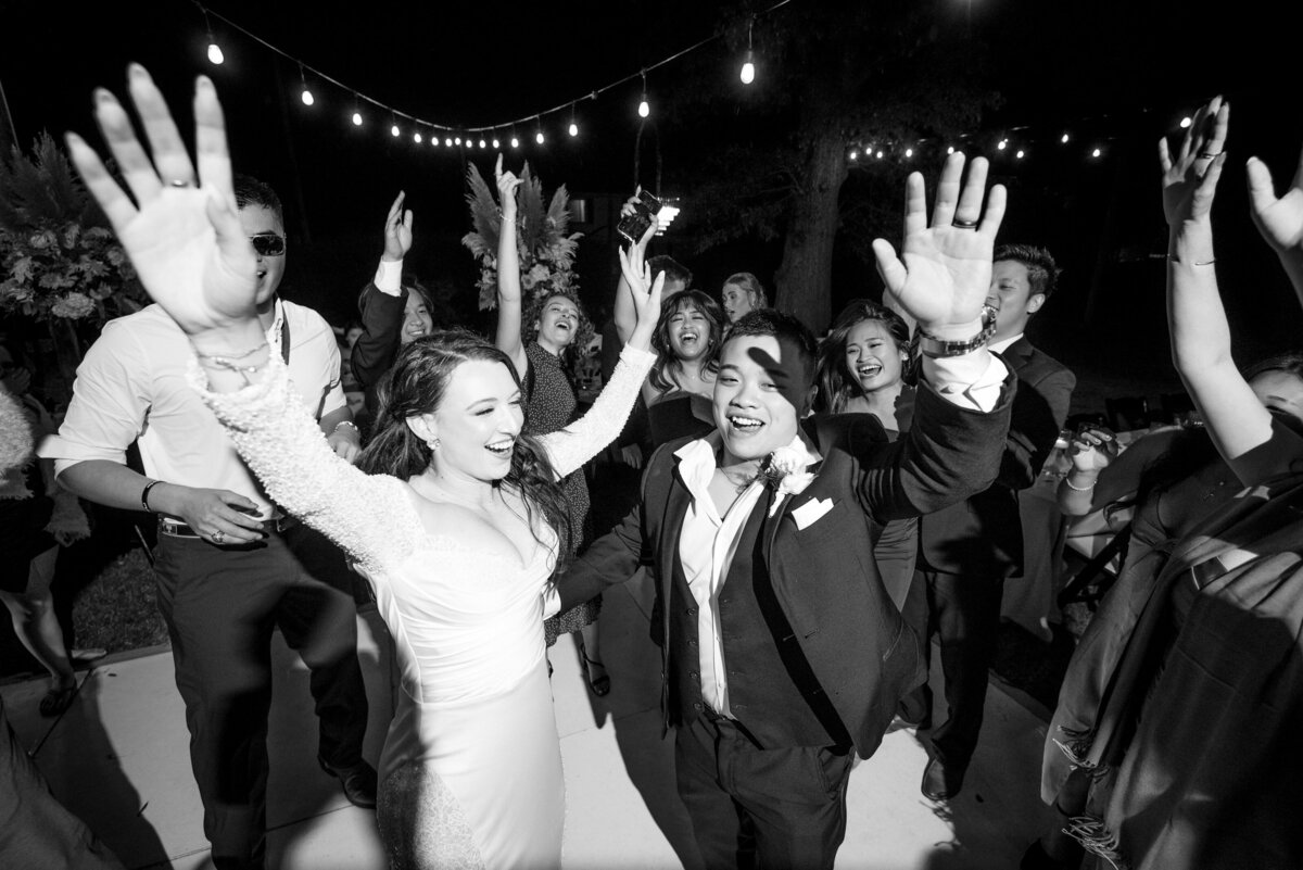 Black and white photograph taken from a high angle pointed down to the bride and groom that have their hands in the air surrounded by their guests at The White Home in Rock Hill, SC