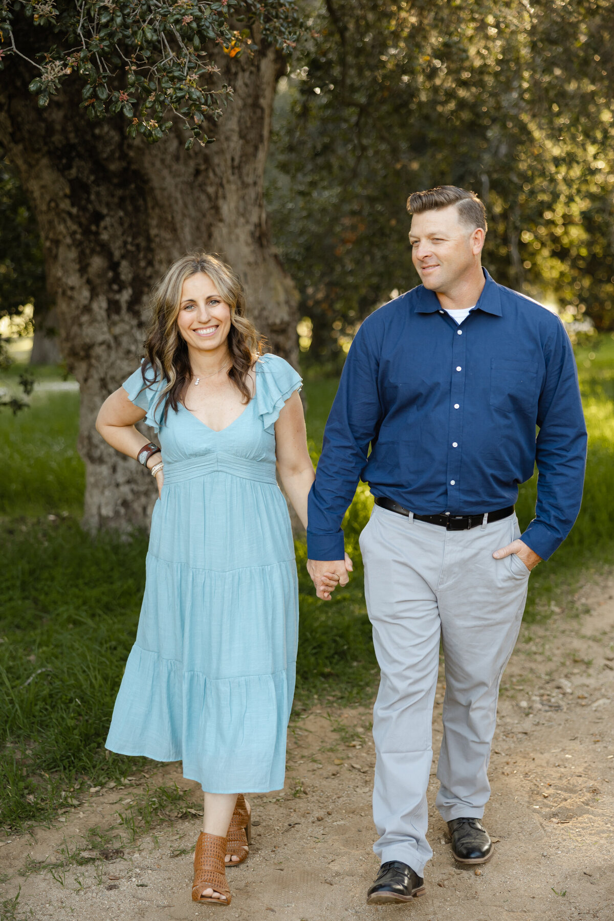 Parents holding hands while walking through grassy outdoor setting. Photographed by Yucaipa family photographer Kaitlyn Dawn Photography.