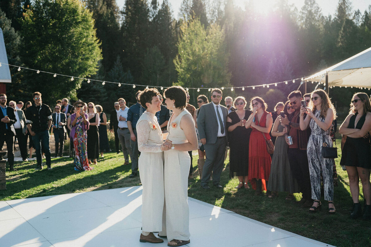 Two women dancing during their first dance at their wedding with guests looking on in the background. 