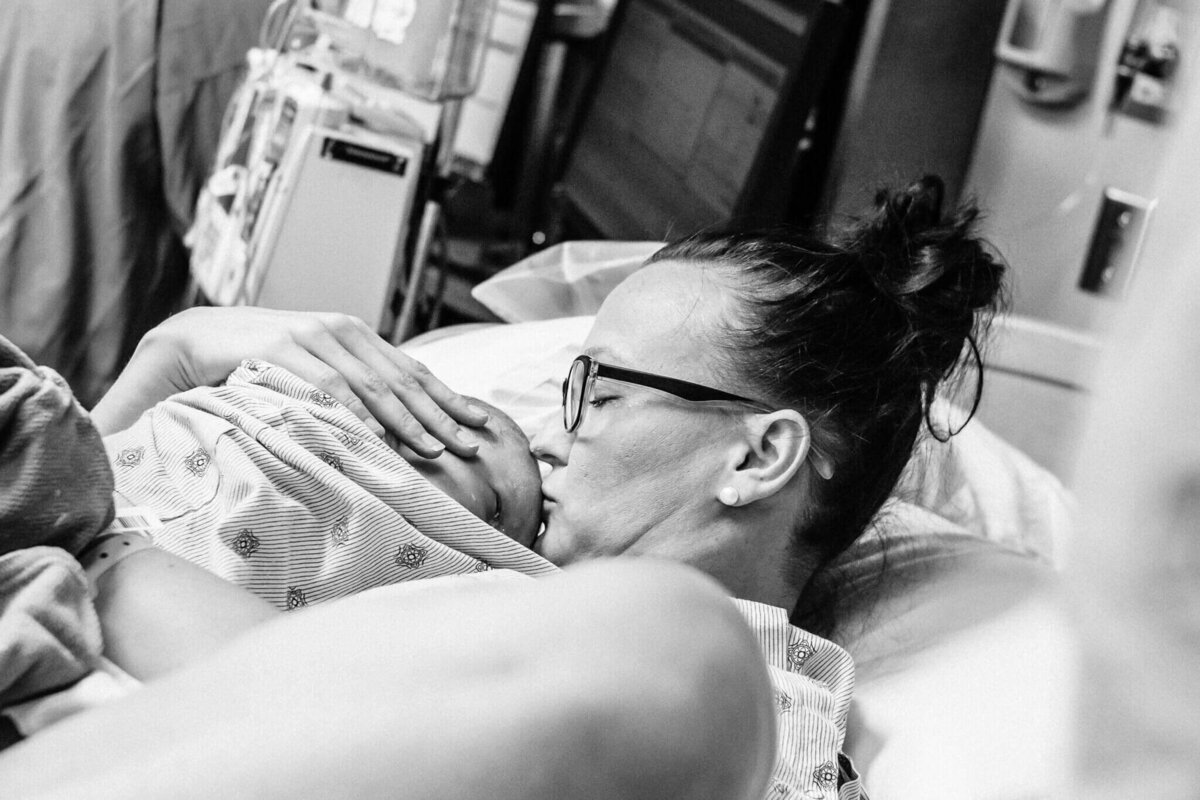 Mom kissing newborn just after birth captured by Claire Thom your birth photographer houston