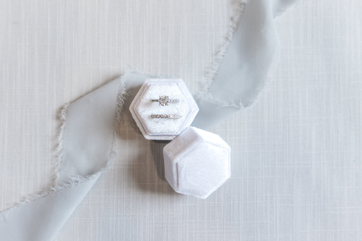 A close up of wedding rings ina white velvet ring box