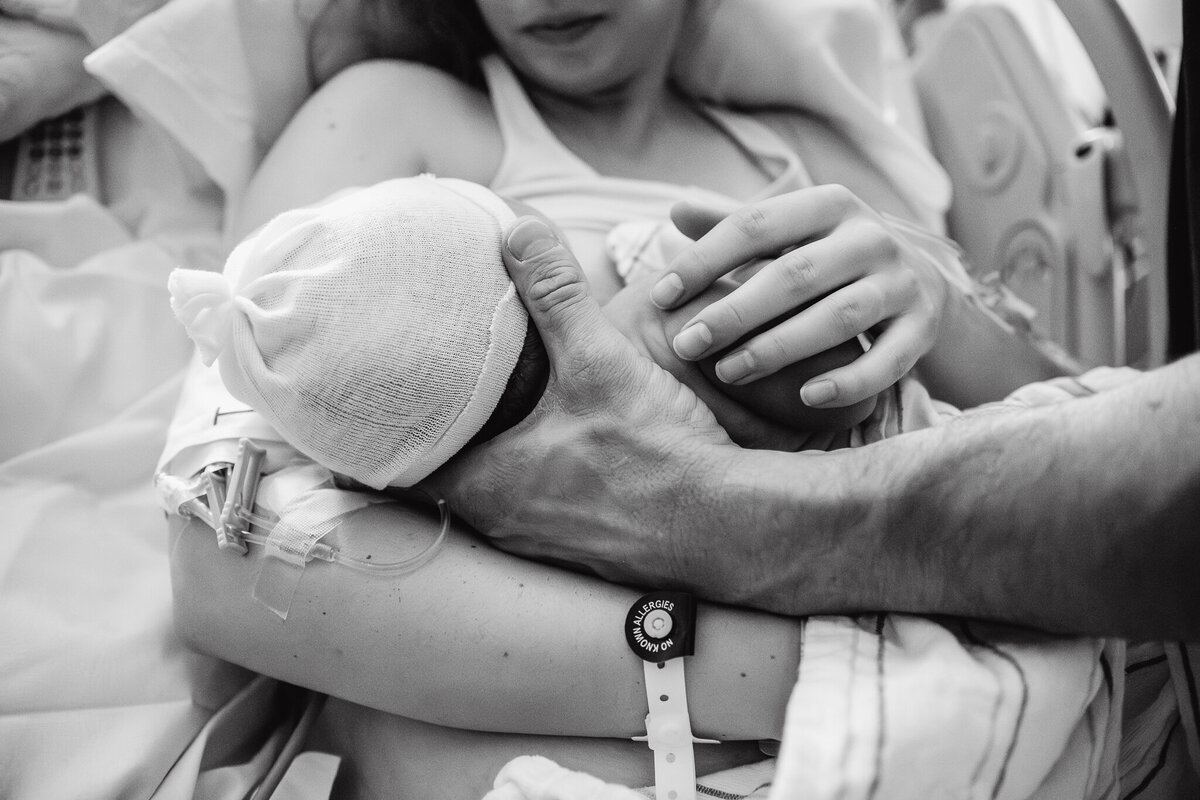 A mother and father hold their newborn baby for the first time. Photo is in black and white. Location was Modesto, California. Shayna Cox was their doula. 