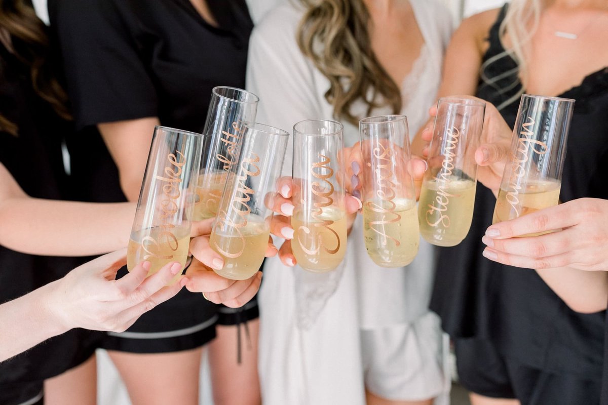 Bride and Bridesmaids cling glasses in a toast while getting ready for the ceremony