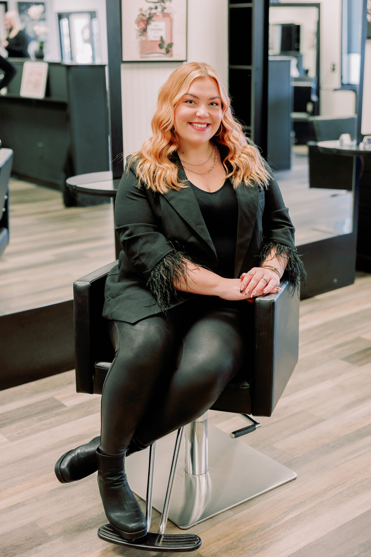 A hairstylist poses in a salon chair.