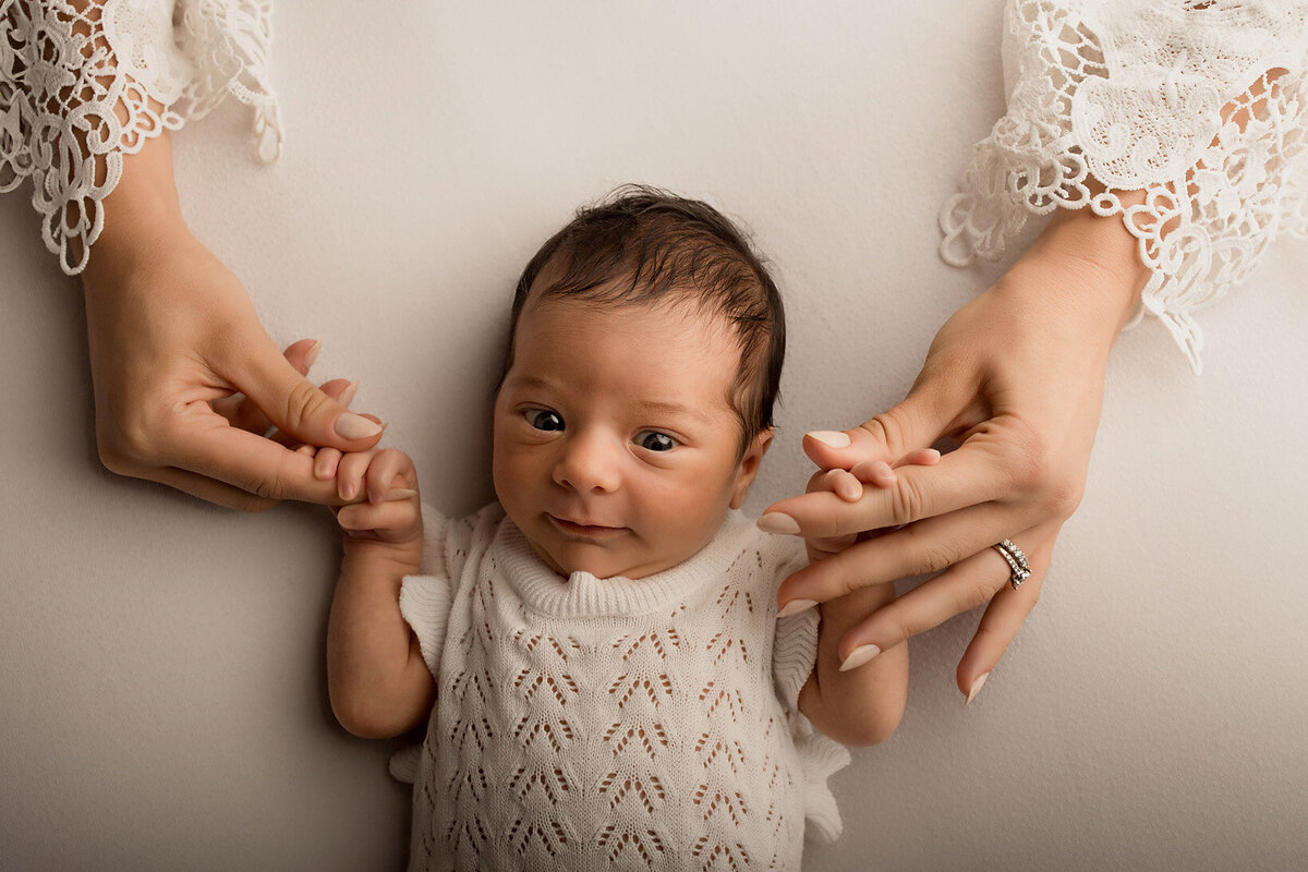 open eyes newborn photo with moms hands wearing lace top