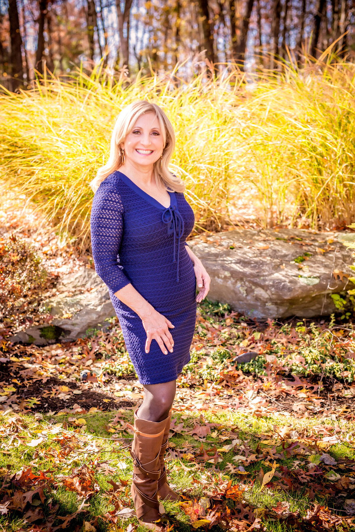 A female dating portrait client wearing a blue dress standing outside in the sunshine