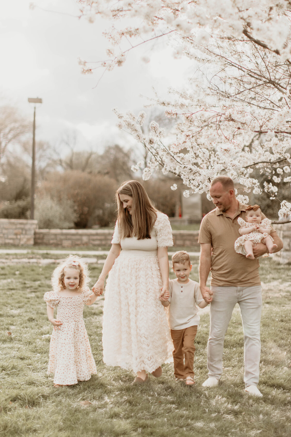Candid photo of the family of five walking through the park hand-in-hand.
