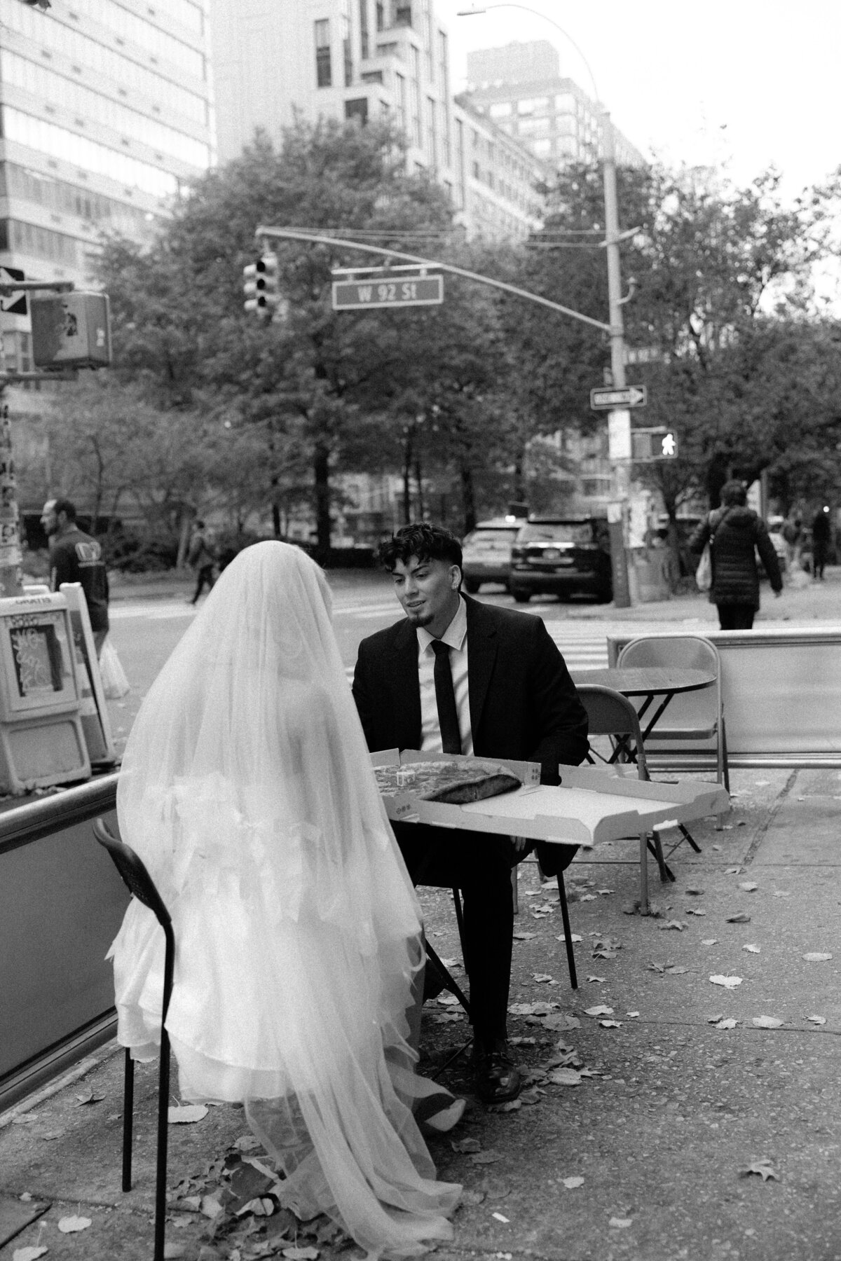 A romantic photo of the couple sharing a pizza under the warm lights of a NYC pizza shop.
