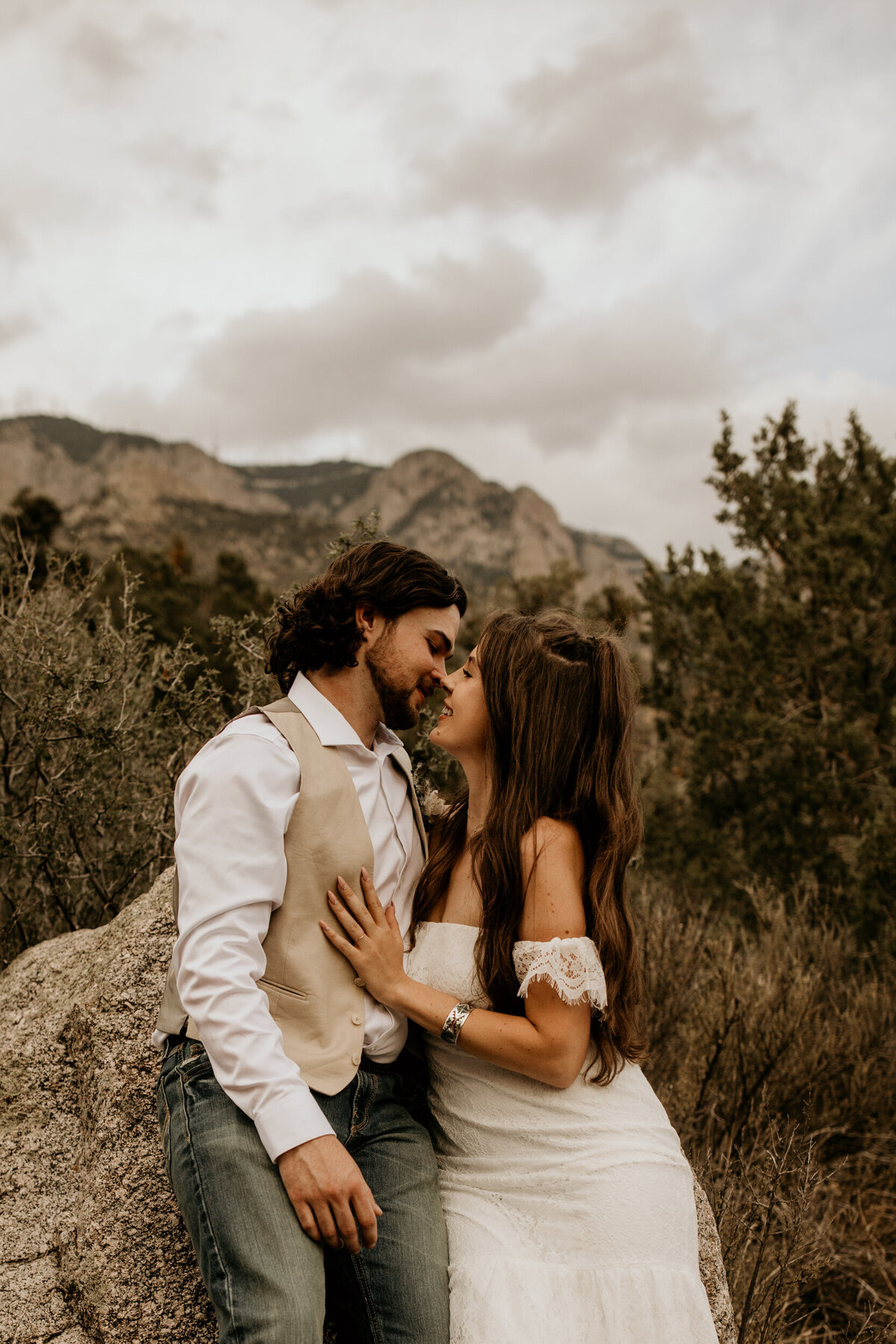 bride and groom sitting against a a rock at the Sandia foothills in Albuquerque