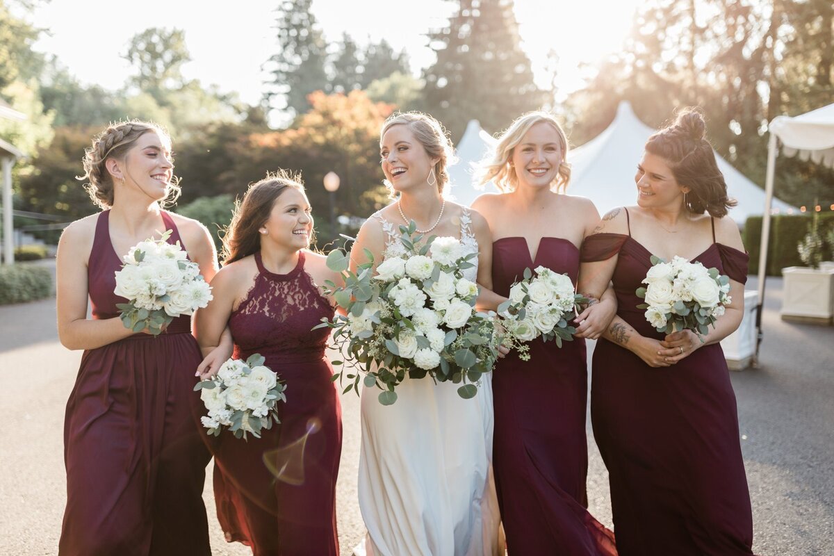 Bridesmaids wearing wine colored dresses with white flower bouquets.