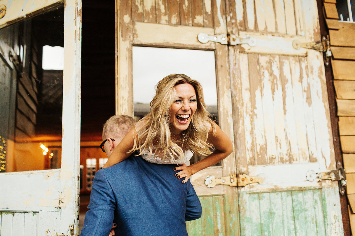 Bride smiling happily whilst being lifted by her husband