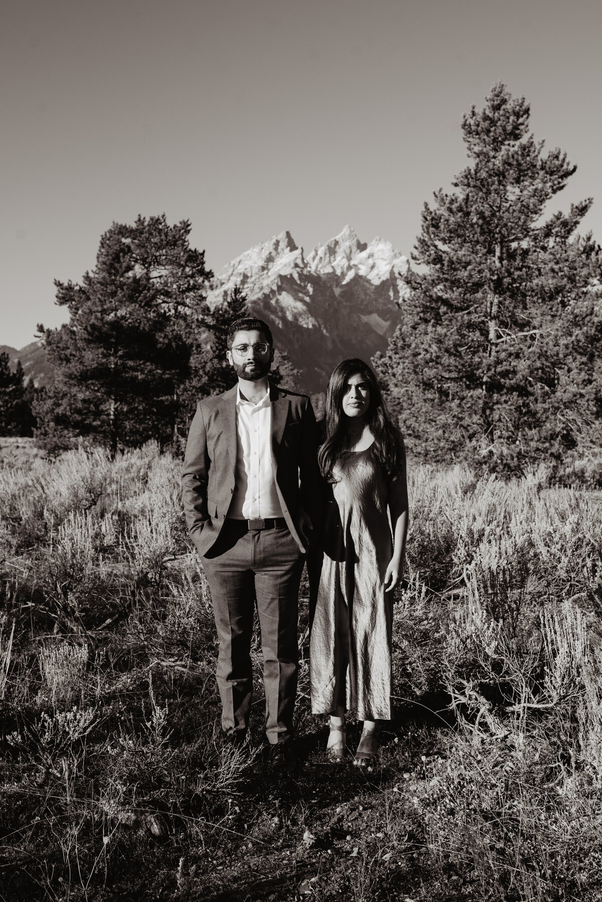 black and white photo of an engagement session in Jackson Hole during the fall with the man and woman in formal attire posing next to each other