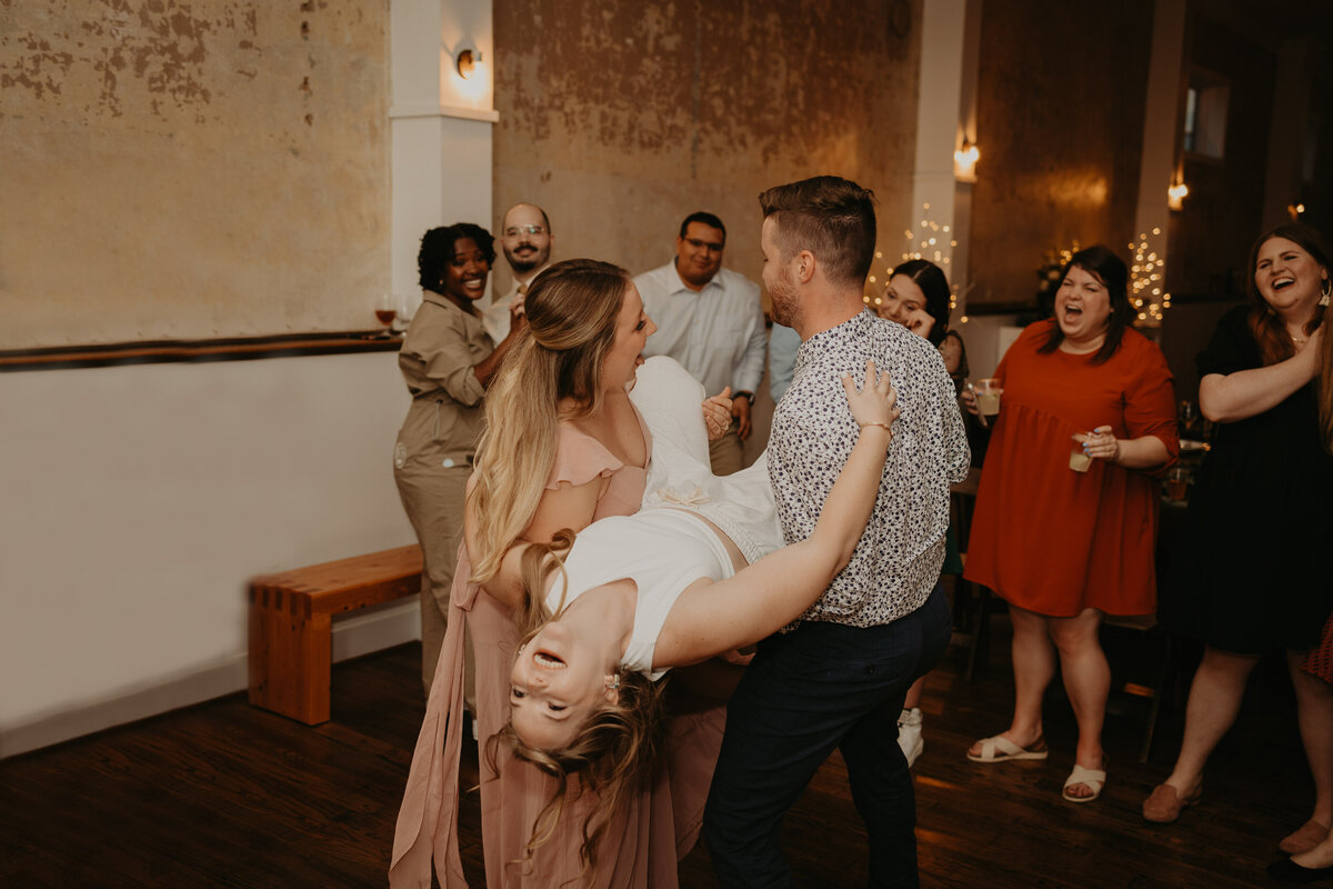 bride is carried on the dance floor by friends