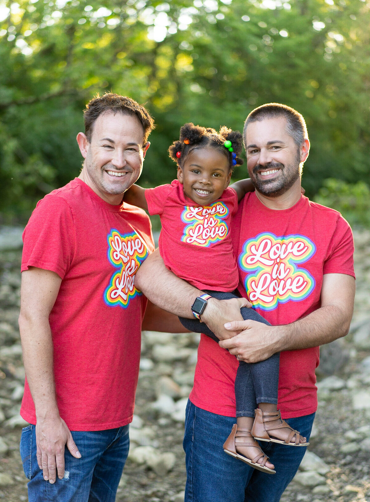 LGBTQ couple, Nick and Sean Bryan, hold their daughter, Piper, in their Love is Love shirts at Creekside Gahanna.