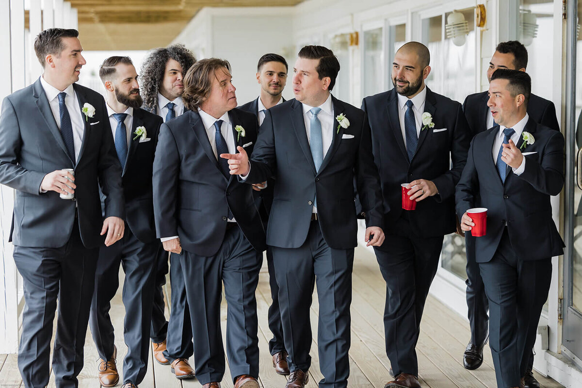 Groom with groomsmen walking along at Long Island wedding