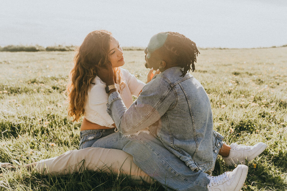 Couple straddling each other and looking at each other lovingly as the sun sets behind them