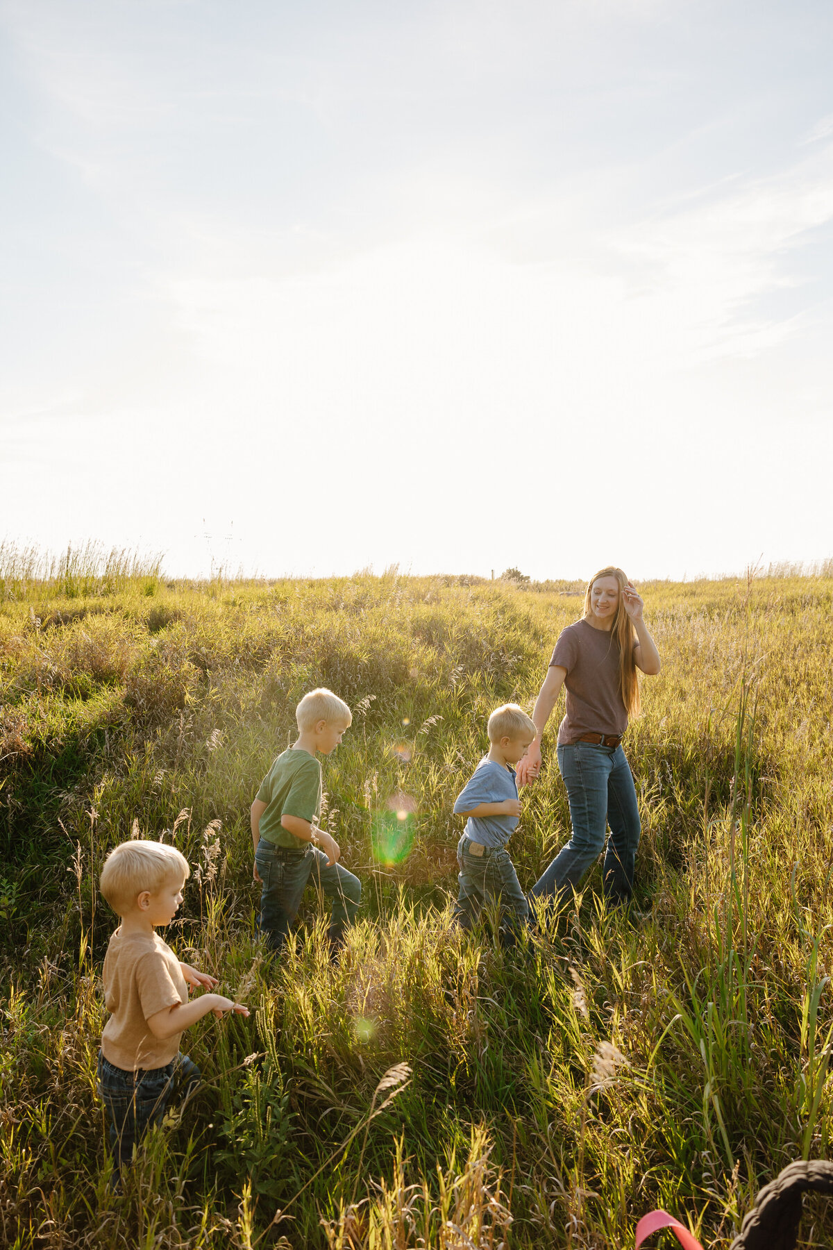 Three kids following their mom as they walk in a field