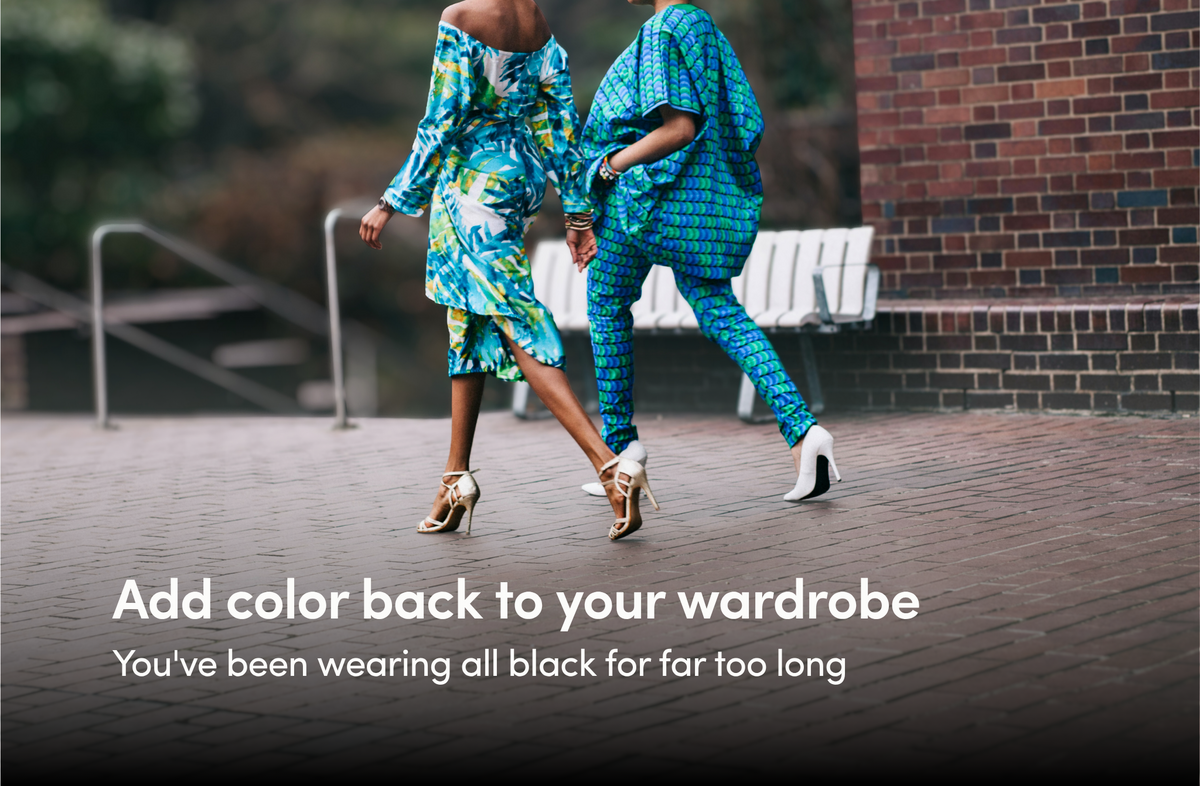 Two black women wearing a mixture of blue and green patterns in their stylish outfits walk away from the camera across bricks in high heels