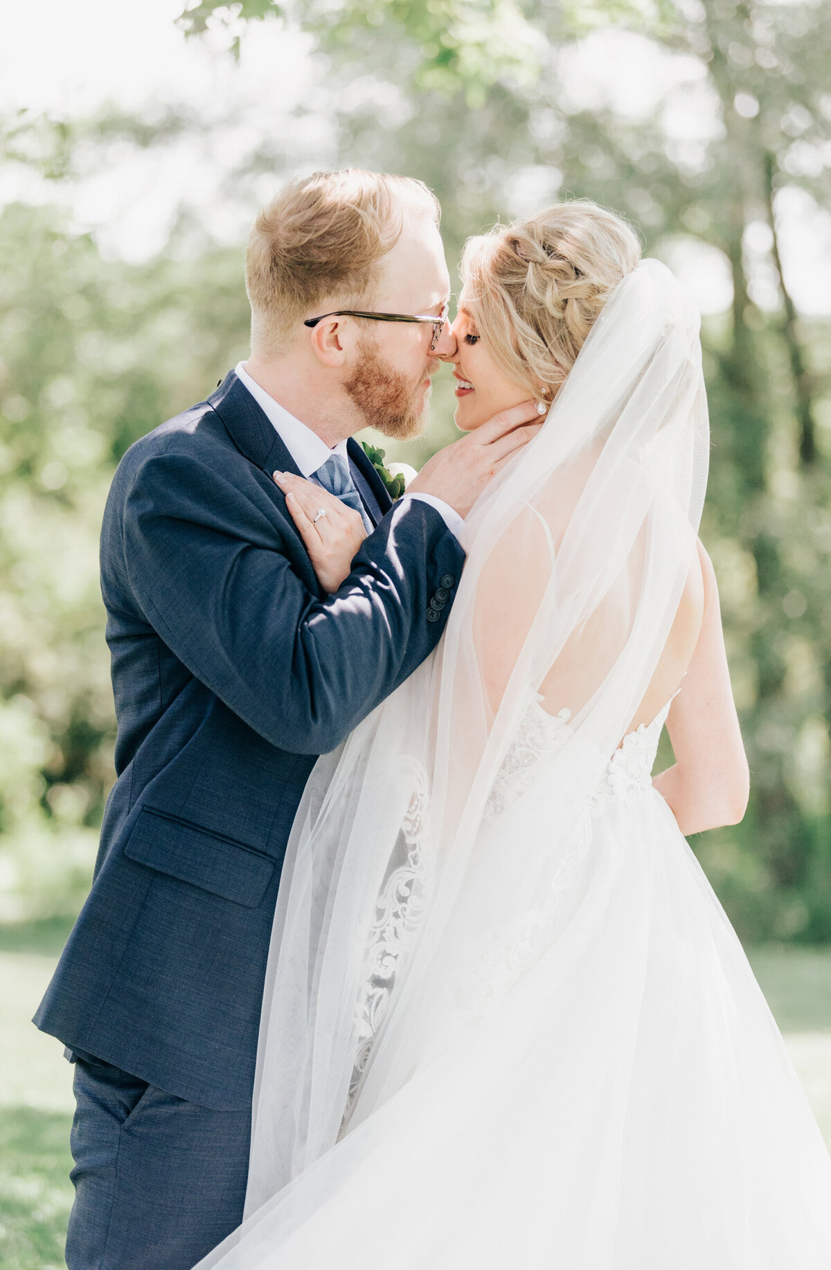 Glamorous wedding portraits of bride and groom kissing, bride's veil flowing in the wind