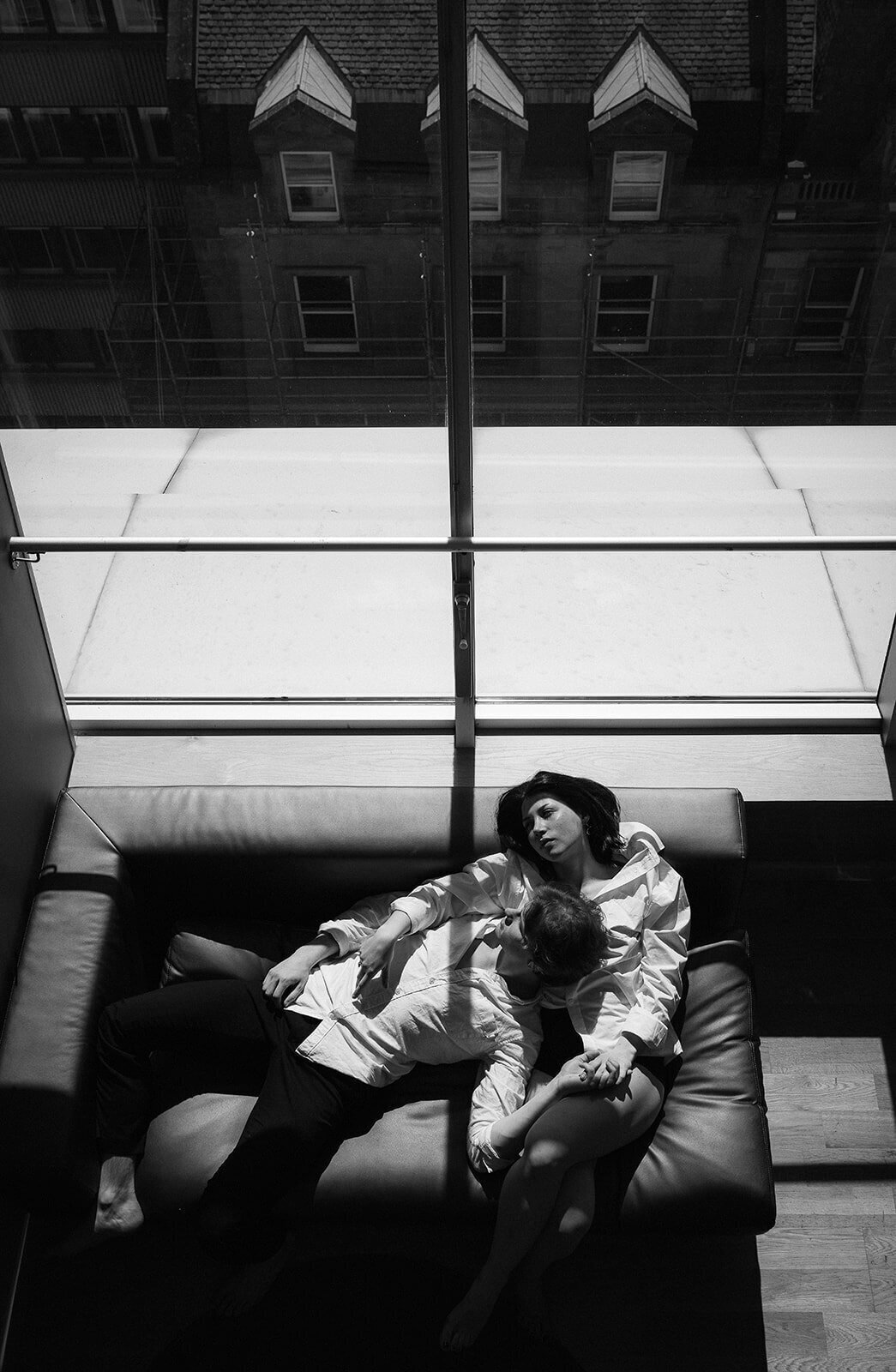 A couple chill on a sofa in a hotel with a panoramic view of the city