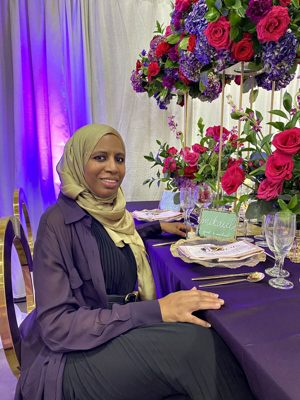  owner, designer, planner sitting elegantly with a stunning arrangement of red and purple florals, including roses and hydrangeas, showcasing a passion for floral artistry and event design, designed by In Full Bloom Event Planning & Design