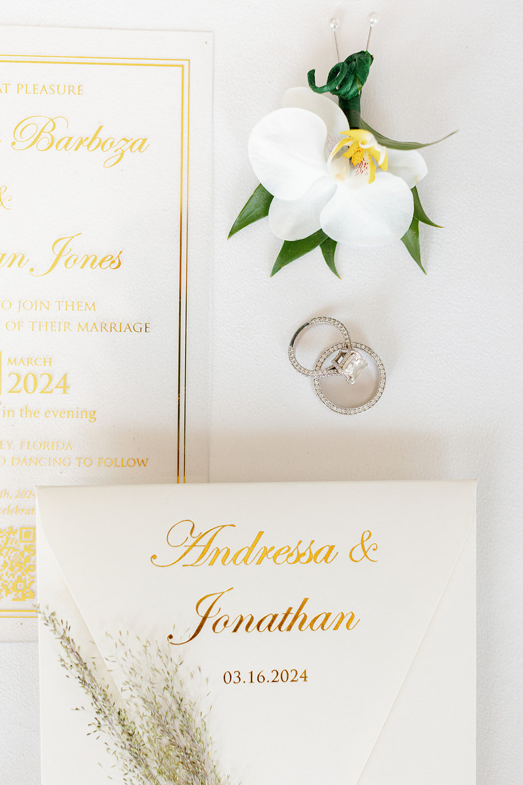 Andressa and Jonathan's elegant wedding invitation suite with gold lettering, wedding rings, and white orchids at Table Key, Islamorada. Captured by Claudia Amalia, destination wedding photographer.