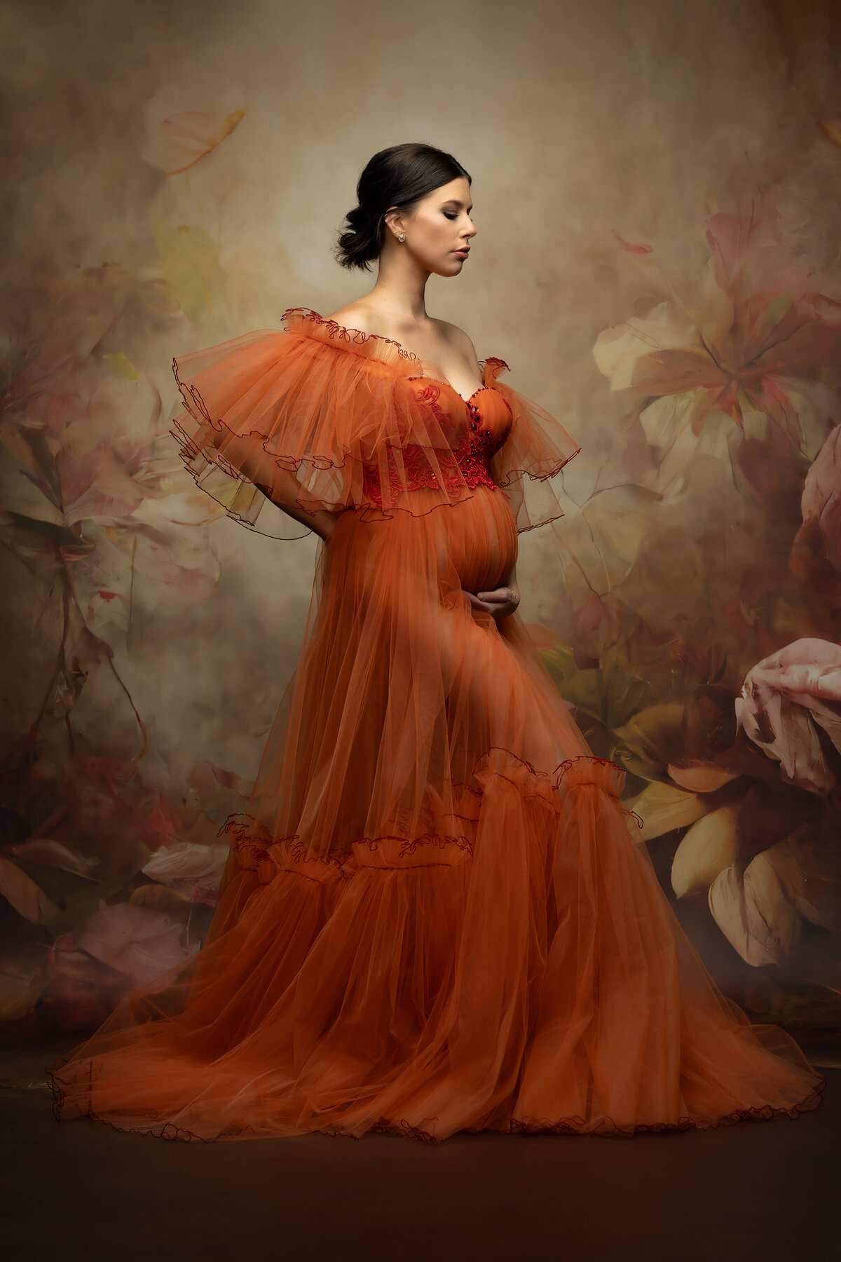 Dallas maternity photography with a seasonal fall inspiration. Stunning expecting woman wearing an orange tulle gown with beautiful warm flowers behind.