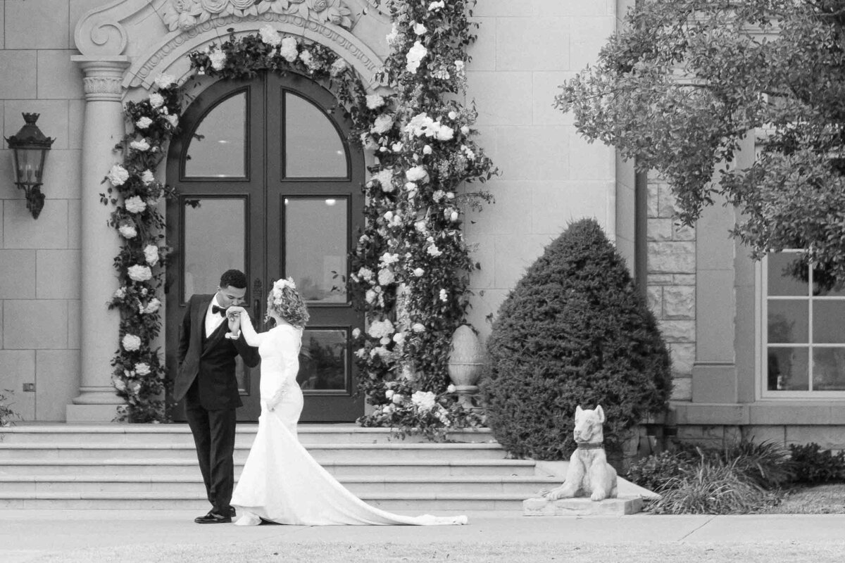 Groom kisses brides hand in front of The Olana Venue Dallas Wedding Venue