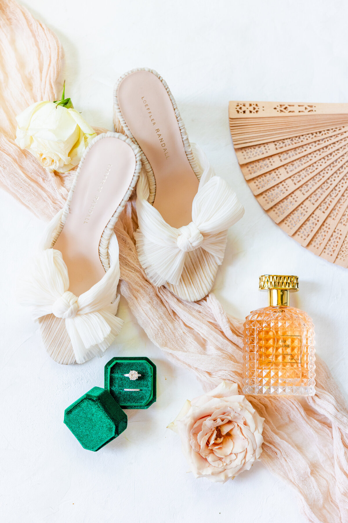 luxury wedding day details with hunter green ring box, glass perfume bottom, a fan and white bow heels photographed by Tracy Waldrop Photography in Charleston, South Carolina