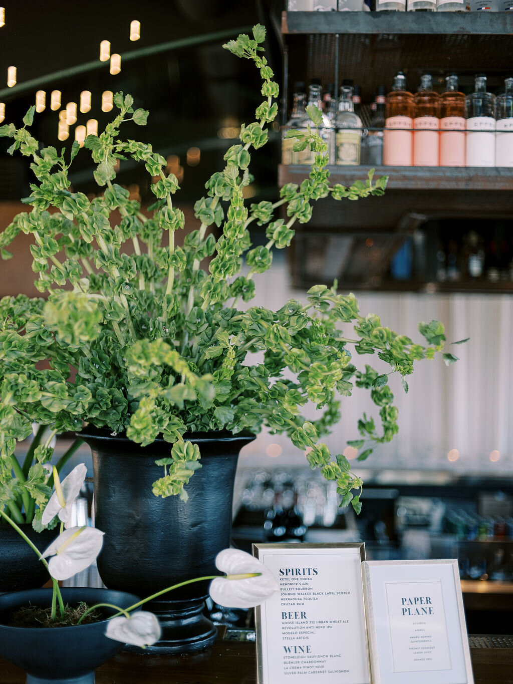 A large black vase filled with fresh greenery sits atop a stylish bar counter.
