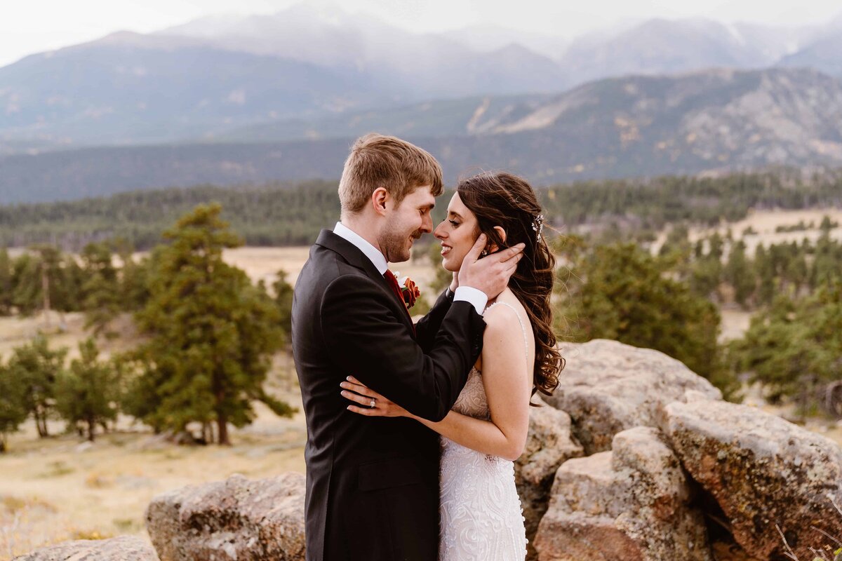 Bride and groom share an intimate embrace on rocky outcroppings with sweeping mountain views at 3M Curve in Rocky Mountain National Park.
