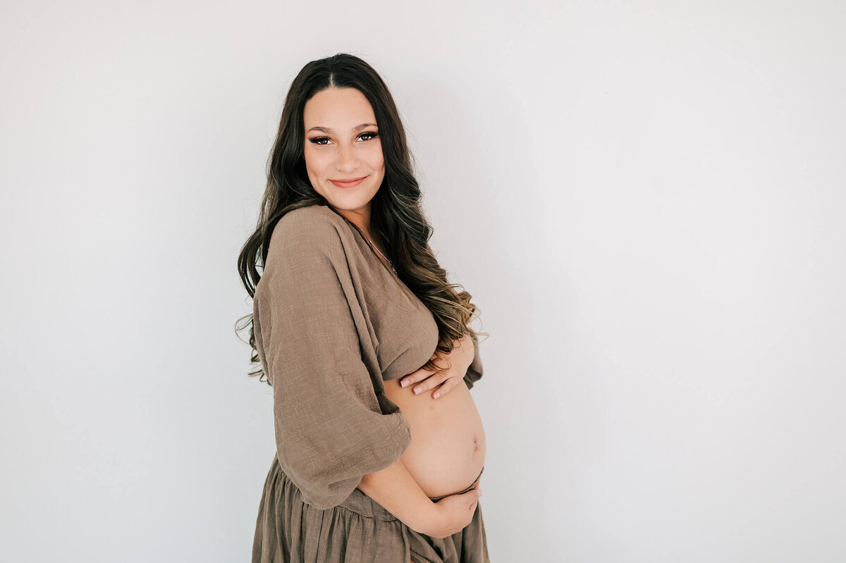 maternity photo of mom holding belly and smiling