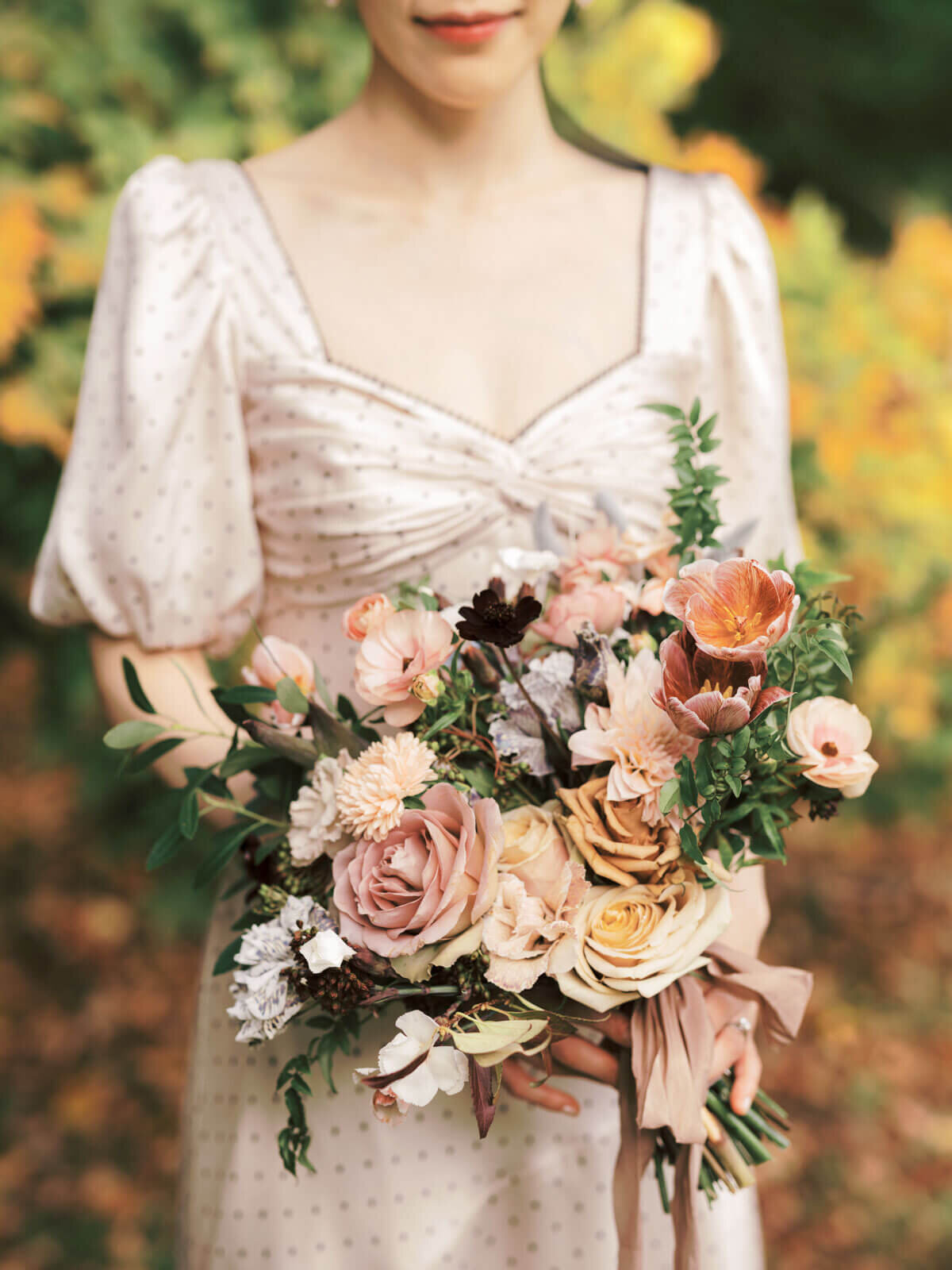 Close-up shot of the engaged woman's bouquet with pretty peach flowers at Planting Fields Arboretum, NY. Image by Jenny Fu Studio