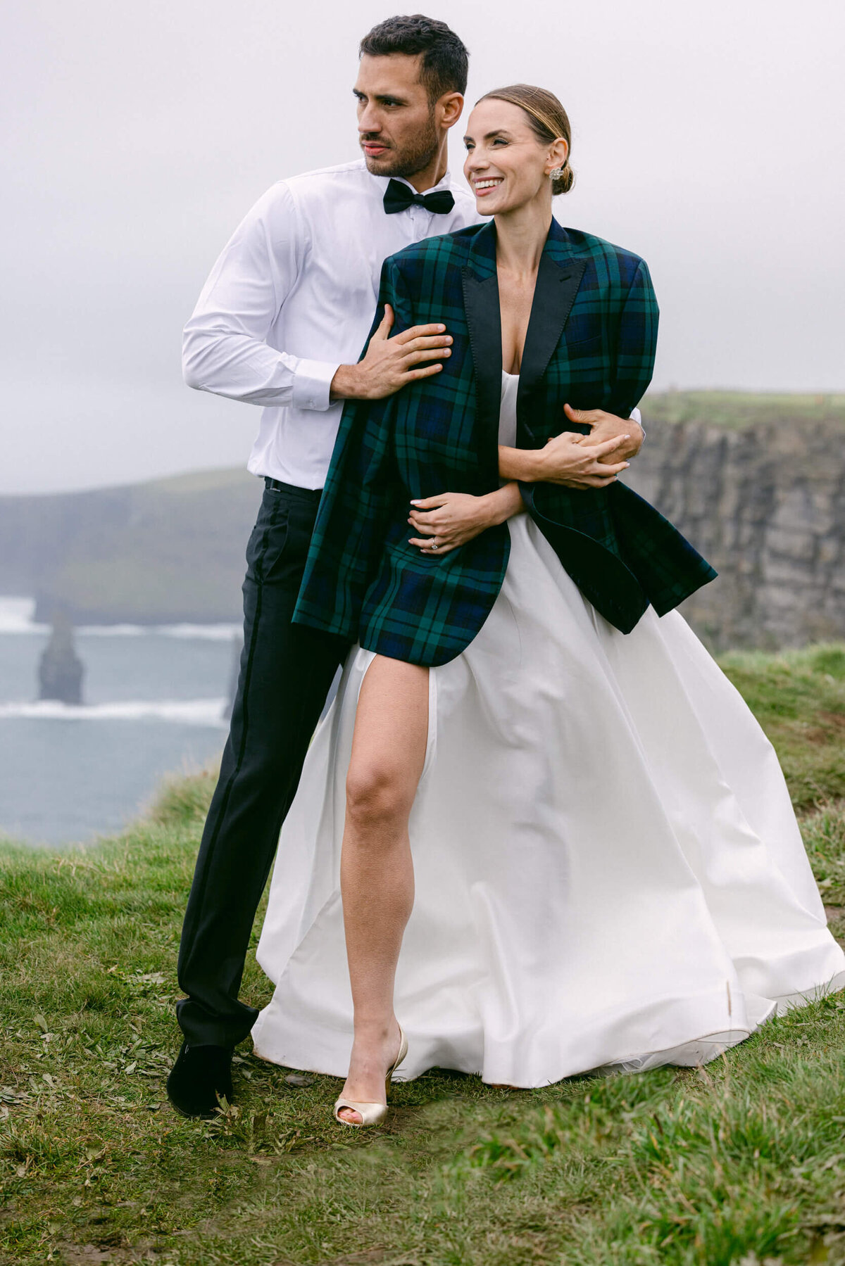 A picture of a couple who got married taken at the top of the cliffs of moher with the bride and groom in the centre and the cliffs in the background
