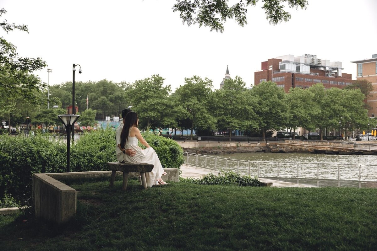 Couple snuggled up, sitting on stone ledge by the river