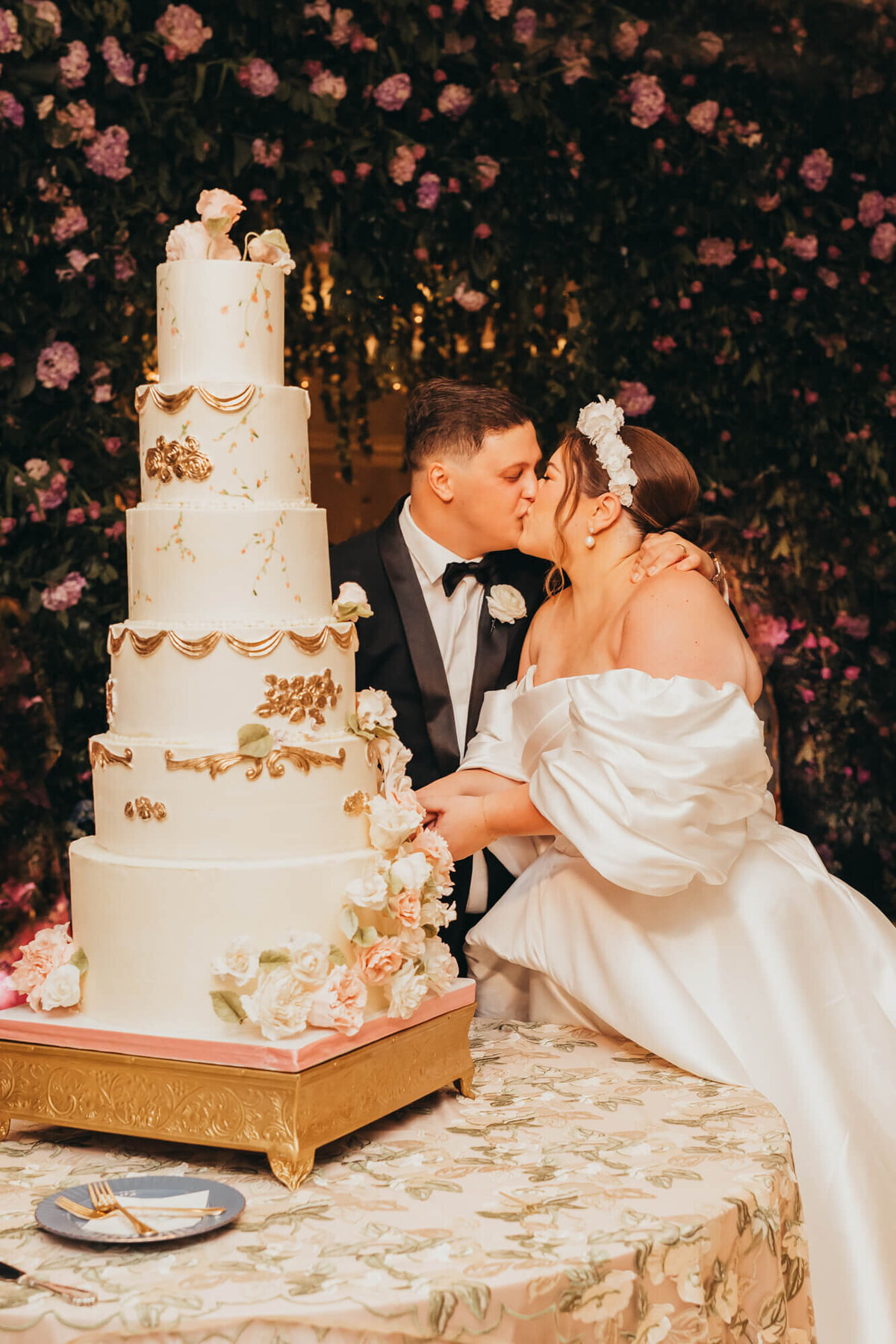 bride and groom kiss while cutting their cake.