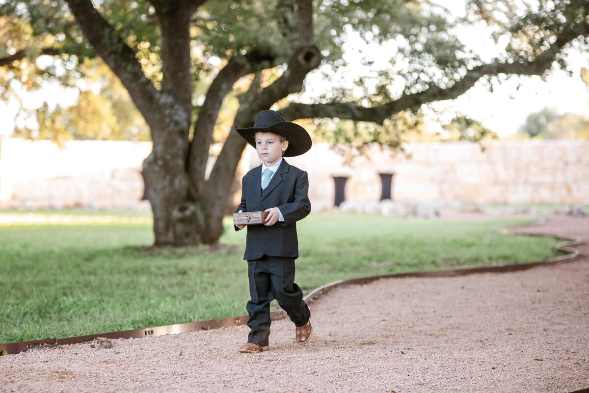 ring bearer in cowboy hat 5 year old walks down aisle at La Dolce Vita wedding New Braunfels Texas