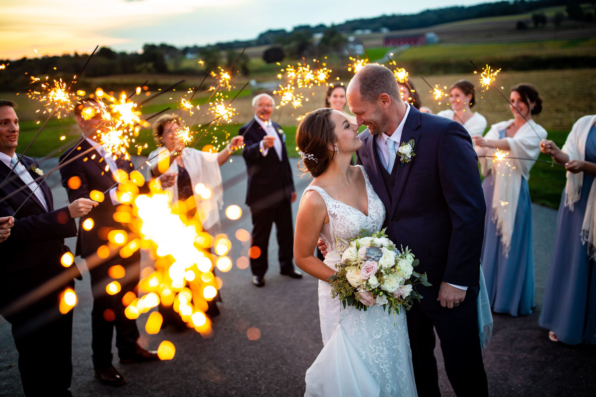 A bride and groom laugh while in a sparkler exit.